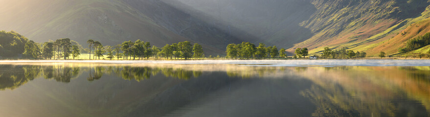 Huge panoramic view of pine trees a long the shoreline of Buttermere with reflections in the lake. © _Danoz