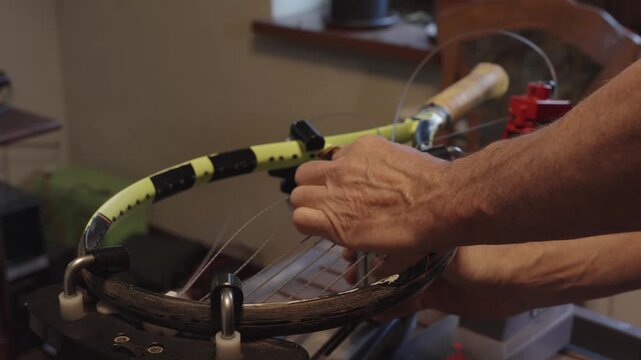 Manual stringing of a tennis racket on machine	