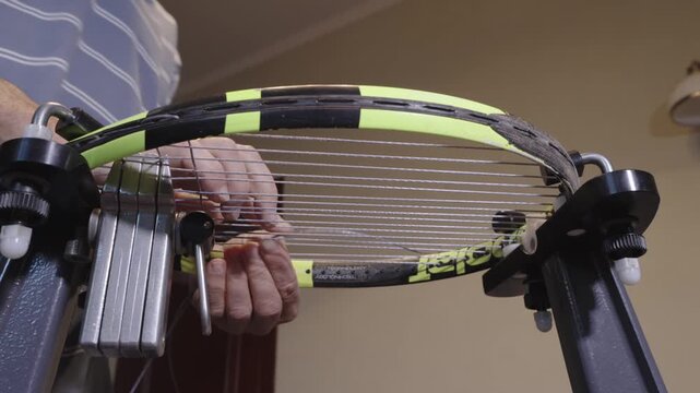 Manual stringing of a tennis racket on machine