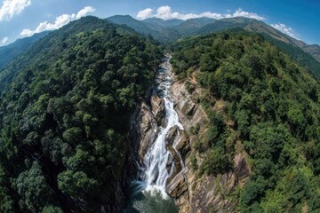 Majestic waterfall cascades through a lush, green valley, surrounded by towering mountain ranges.