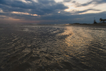 Low tide sea water retreating from sandy beach.
