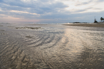 Low tide sea water retreating from sandy beach.