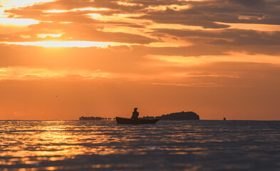 Orange sunrise reflecting on gentle sea waves.