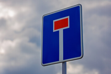 Close-up of Dead End road sign against gray overcast sky background