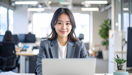 ノートパソコンに向かう日本人女性会社員の仕事風景 – Young Japanese Businesswoman in Gray Suit Working on Laptop in Office