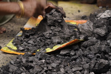 A person handling black coal pieces, showing hard manual work and energy source mining concept, symbolizing industrial power and fuel