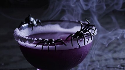 Dark purple drink features black spiders on the rim, with swirling smoke enhancing the spooky ambiance, ideal for Halloween and Day of the Dead gatherings