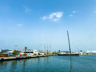 Cruising the serene harbor under a clear blue sky with sleek sailboats and modern buildings dotting the waterfront