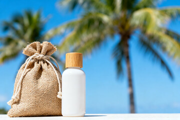 White bottle with wooden cap and burlap sack on a table against a tropical palm tree background