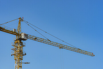 The building tower crane is working under the blue sky background