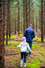Father and daughter hiking together in a coniferous forest in Czech Republic. Family bonding, outdoor exploration and early childhood connection with nature.