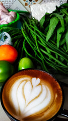 A cup of latte among the vegetables for. Cooking preparation. Household activities.
