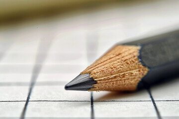 Close-up of a sharpened graphite pencil on grid paper showcases precision and detail in a creative
