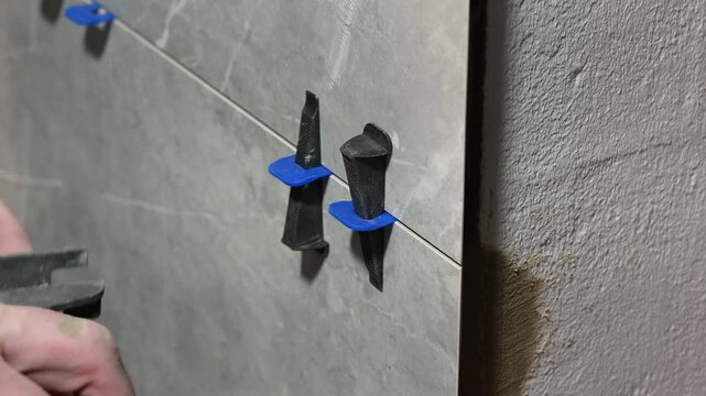 The master tiler inserts the blades into the tile leveling system and tightens it with a special tool