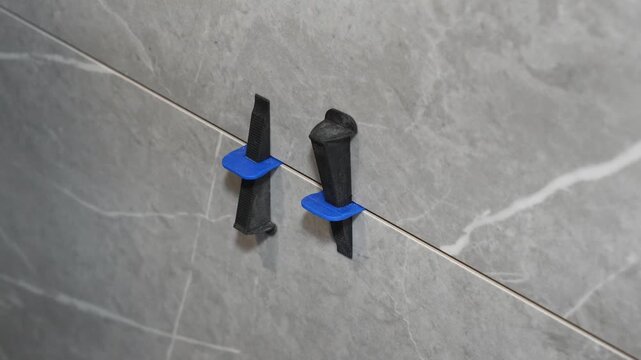 The master tiler inserts the blades into the tile leveling system and tightens it with a special tool
