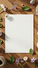 Blank white paper sheet surrounded by delicate wildflowers, green leaves, and twine on a rustic wooden surface, creating a serene and inviting atmosphere for creative projects and designs