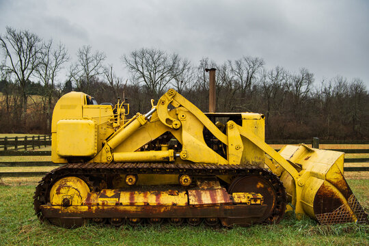 Side view of a yellow bulldozer in a field in winter in the midwest