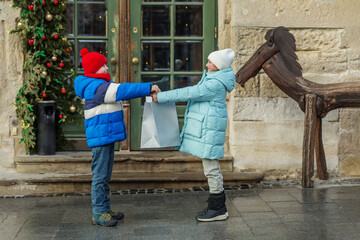 Kids exchanging gift bag outside during winter holidays