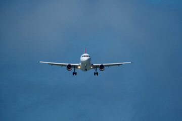 Airplane in the cloudy sky. An airplane flying near an airfield with its landing gear down