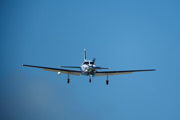 Small propeller airplane flying in the blue sky on a sunny day. Single Engine Turboprop Aircraft Landing