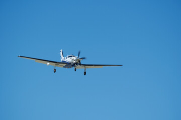 Small propeller airplane flying in the blue sky on a sunny day. Single Engine Turboprop Aircraft Landing