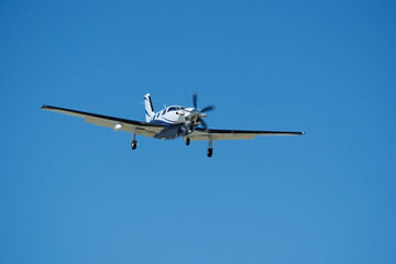 Small propeller airplane flying in the blue sky on a sunny day. Single Engine Turboprop Aircraft Landing