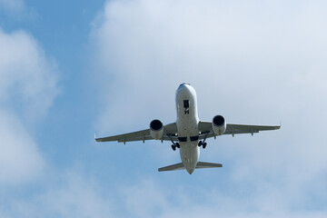 Airplane in the cloudy sky. An airplane flying near an airfield with its landing gear down
