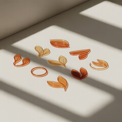 Various translucent leaf shaped objects and a ring scattered on a light colored surface with dappled shadows