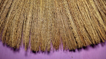 Fototapeta premium Broom bristles fanning out on purple surface showing texture and detail, suggesting cleaning or domestic work, creating a simple and rustic feel.