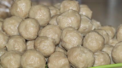 Pile of fresh, homemade meatballs sits on a plastic plate, ready to be cooked for a delicious and hearty meal, showcasing culinary simplicity.