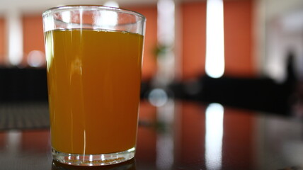Refreshing glass of orange juice sitting on a polished table in a modern cafe, creating a bright and inviting atmosphere.