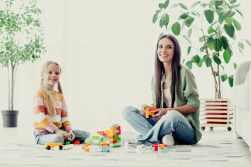 Naklejka premium Mother and daughter playing together with building blocks in a cozy living room, expressing family bonding and fun