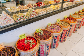 Colorful Turkish delight and herbal teas displayed in traditional barrels inside a local shop, showcasing sweet treats and dried floral blends.