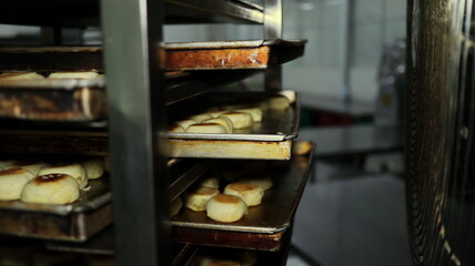 Freshly baked pastries cooling on trays in a commercial bakery after being removed from the oven, showcasing the baking process and artisanal food production.