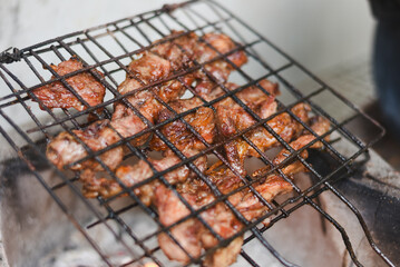 close-up shot of marinated meat grilling on a metal wire rack over an open flame or charcoal.