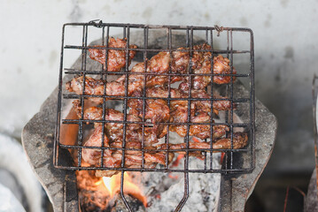 close-up shot of marinated meat grilling on a metal wire rack over an open flame or charcoal.