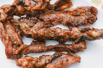 close-up overhead shot of several pieces of cooked, grilled, or fried meat served on a plate