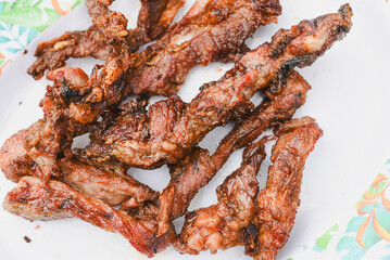 close-up overhead shot of several pieces of cooked, grilled, or fried meat served on a plate