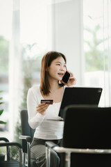 Young woman holding a credit card while shopping online with a laptop, symbolizing e-commerce, digital payments, and modern lifestyle.