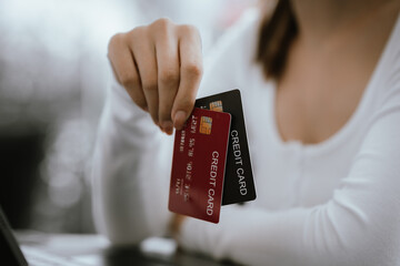 Close-up of woman holding credit card and typing on laptop, making online payment and shopping securely.