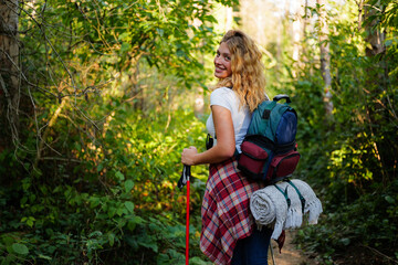 Obraz premium Young woman hiking actively in green forest turning smiling