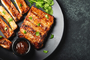 Hot grilled spare ribs from a summer BBQ served on a plate with sauce. Top view. Copy space