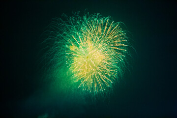 Firework sparks with smoke plumes are visible in the night sky, with colored lights and smoke forming a festive display, visible from land and water, creating a striking firework scene.