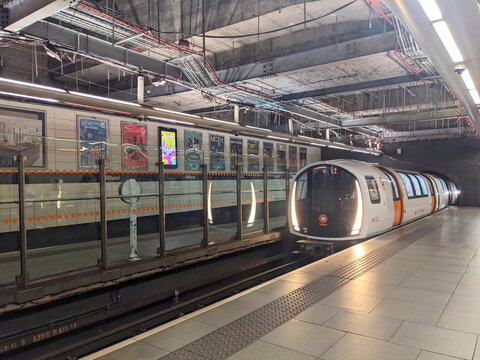 Modern Glasgow Subway train arriving at the industrial-style Hillhead underground station platform