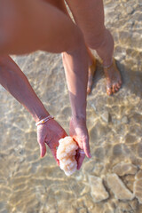 girl holds salt crystals in hand. female hand holds natural salt crystals on salty sea background. White natural salt. dead sea. israel.