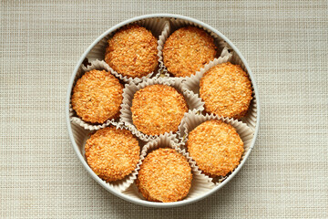 Sesame cookies wrapped in paper wrappers and placed in a metal box. Top view. Closeup