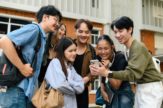 Happy group of college students bonding over a smartphone, showing teamwork, identity acceptance, and the role of technology in connecting diverse communities