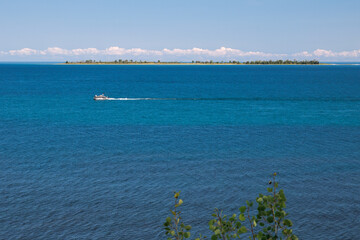 Serene Barrier Island with Tour Boat, Coastal Trees, Barren Beach, and Rocks, under Blue Sky
