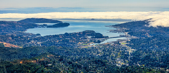 Panoramic view from Mount Tamalpais East Peak overlooking San Francisco Bay, Richmond San Rafael Bridge, Angel Island, and rolling hills of Marin County under fog and blue sky, California USA