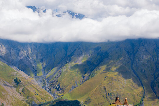 Scenic view of the historic Gergeti Trinity Church set high in the mountains of Georgia near Kazbegi under heavy clouds